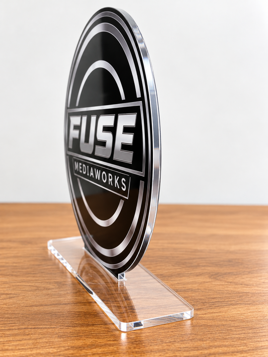 A black and silver oval acrylic plaque featuring the &