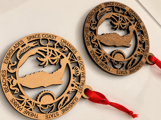 Two round laser-cut wooden coast guard ornaments with red hanging ribbons, displayed on a white background.
