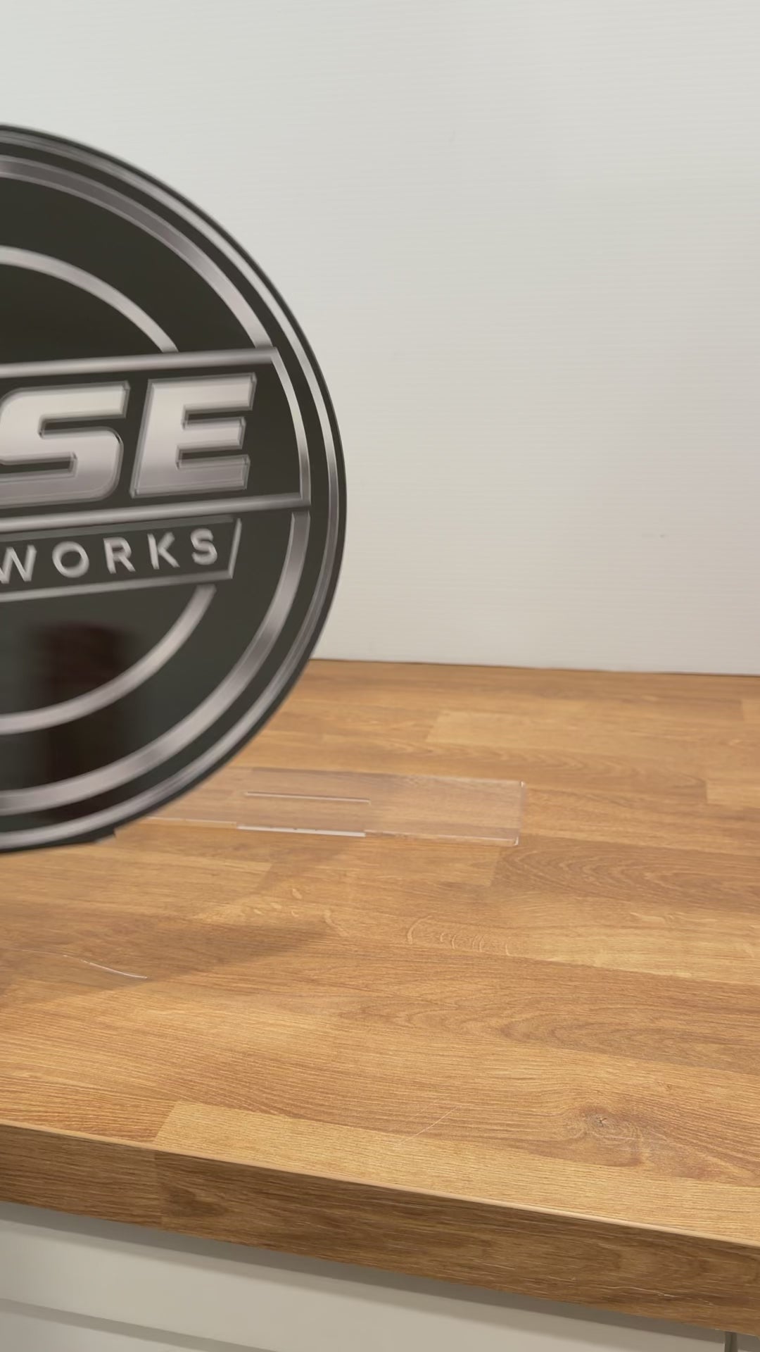A round clear acrylic sign being placed onto a clear stand and spun around to show the front and back