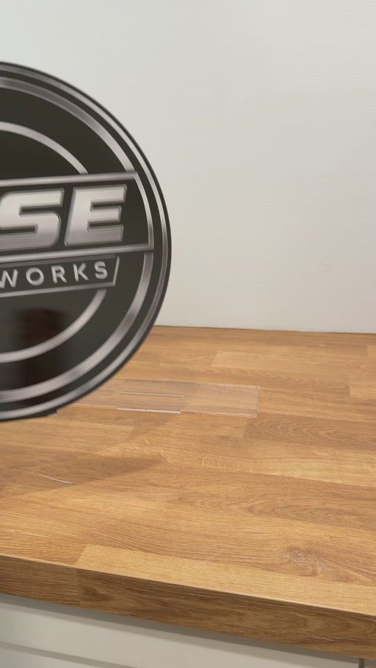 A round clear acrylic sign being placed onto a clear stand and spun around to show the front and back